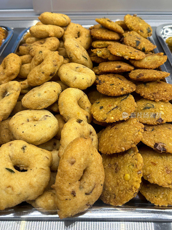 在市场摊位上出售的亚洲街头小吃的图片，uludu wade / dhal vada，美味的印度甜甜圈/甜甜圈放在热金属托盘上，随时可以出售和食用，高处的视野